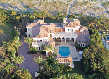 An aerial shot of a beach front home with a pool
