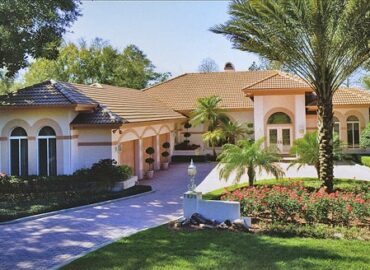 A large home with a circular driveway, and nice landscaping