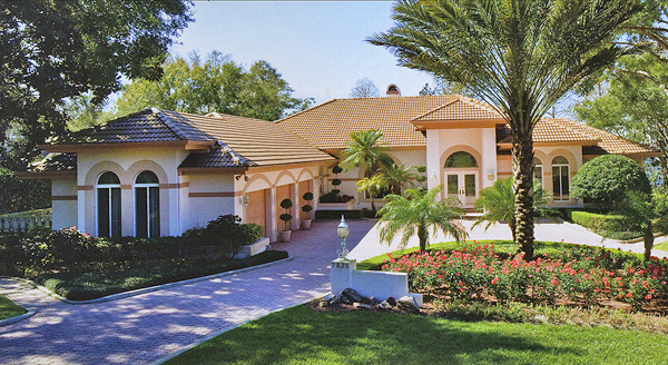 A large home with a circular driveway, and nice landscaping