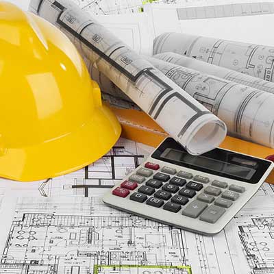 A yellow construction hat, blueprints, and a calculator