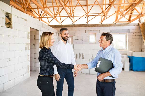 A married couple meeting up with the construction manager to talk about the status of their home that is under construction