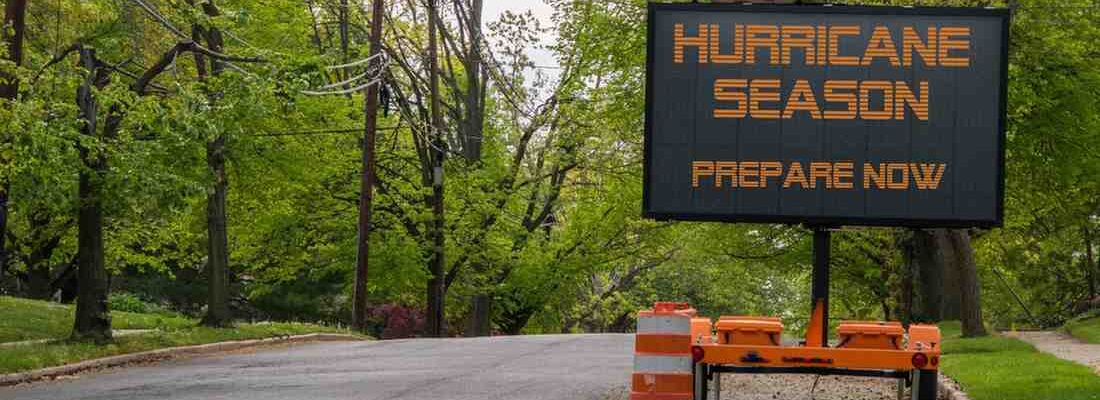 Digital electronic mobile road sign that says Hurricane Season prepare now, on the side of a tree lined neighborhood road