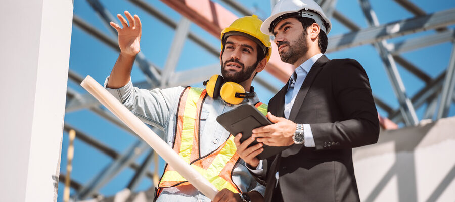 Civil engineer and construction worker manager holding digital tablet and blueprints , talking and planing about construction site